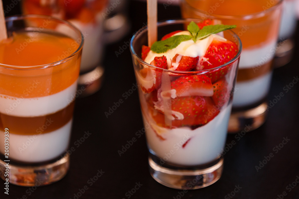 layered dessert with strawberries, biscuit cake and cream cheese on a dark wood background. tinting. selective focus layered dessert with strawberries, biscuit cake and cream cheese on a dark wood background. tinting. selective focus
