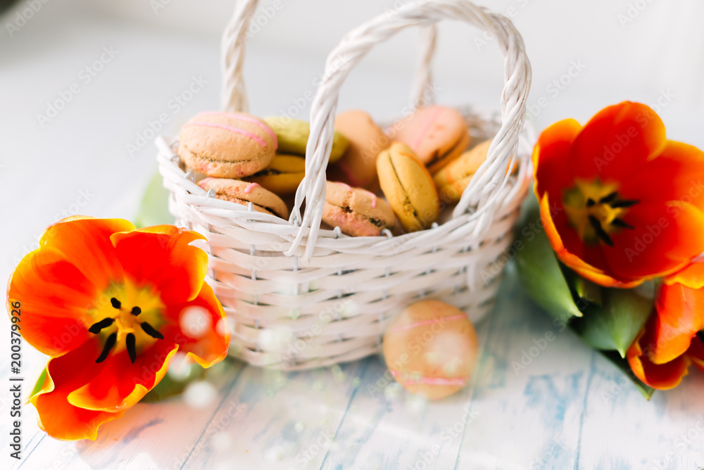 Blossoming tulips with macaroons on a light wooden background. Still life, spring concept