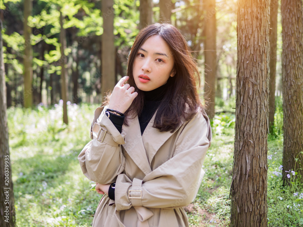 Beautiful young brunette woman posing and staring blankly in forest park. Outdoor fashion portrait of glamour young Chinese stylish lady. Emotions, people, beauty and lifestyle concept. Beautiful young brunette woman posing and staring blankly in forest park. Outdoor fashion portrait of glamour young Chinese stylish lady. Emotions, people, beauty and lifestyle concept.