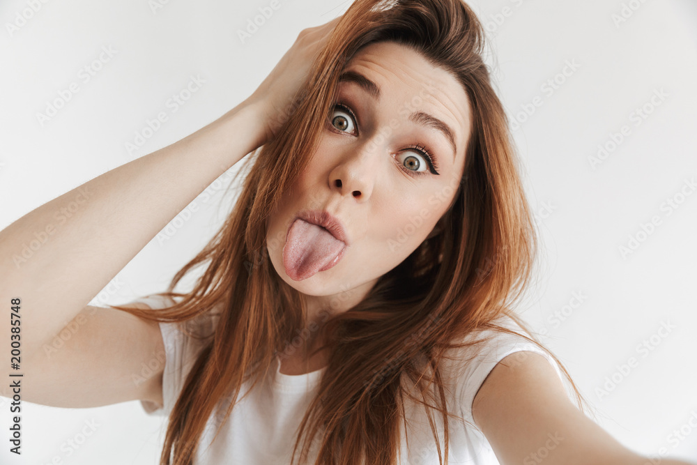Funny woman in casual clothes making selfie while showing tongue