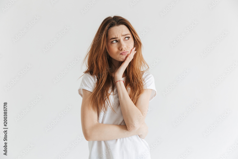 Pensive worried woman in t-shirt touching her cheek Pensive worried woman in t-shirt touching her cheek