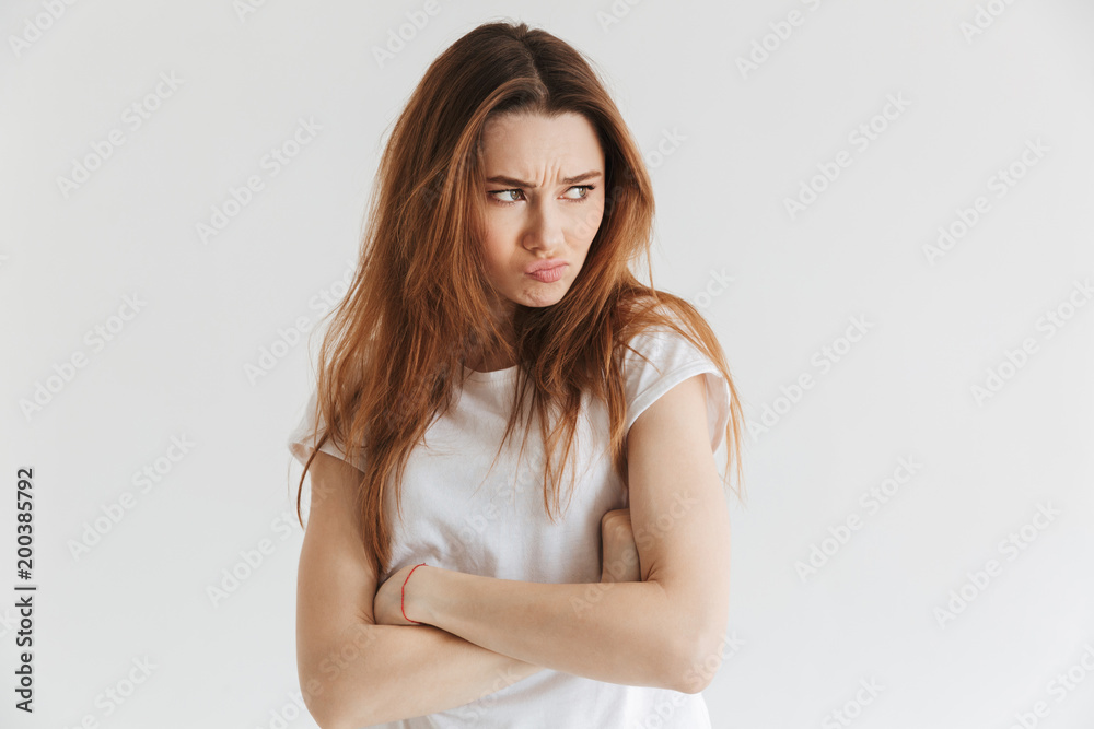 Displeased woman in t-shirt with crossed arms looking at camera Displeased woman in t-shirt with crossed arms looking at camera
