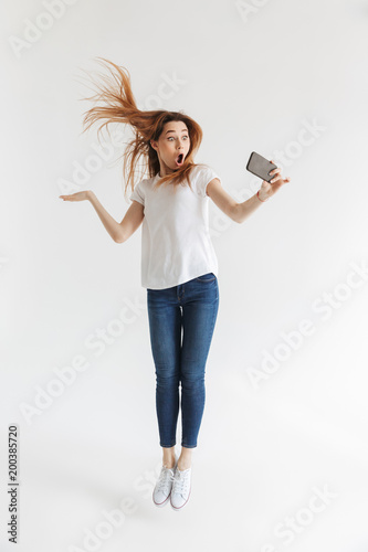 Full length image of Shocked woman in casual clothes jumping