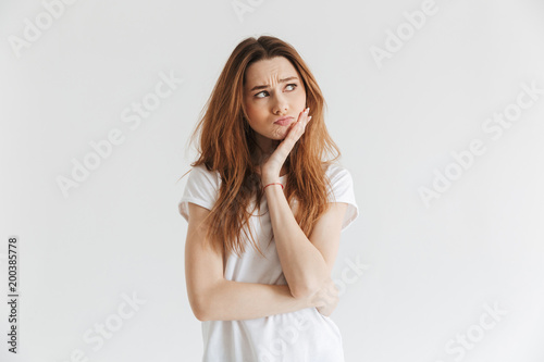 Pensive worried woman in t-shirt touching her cheek