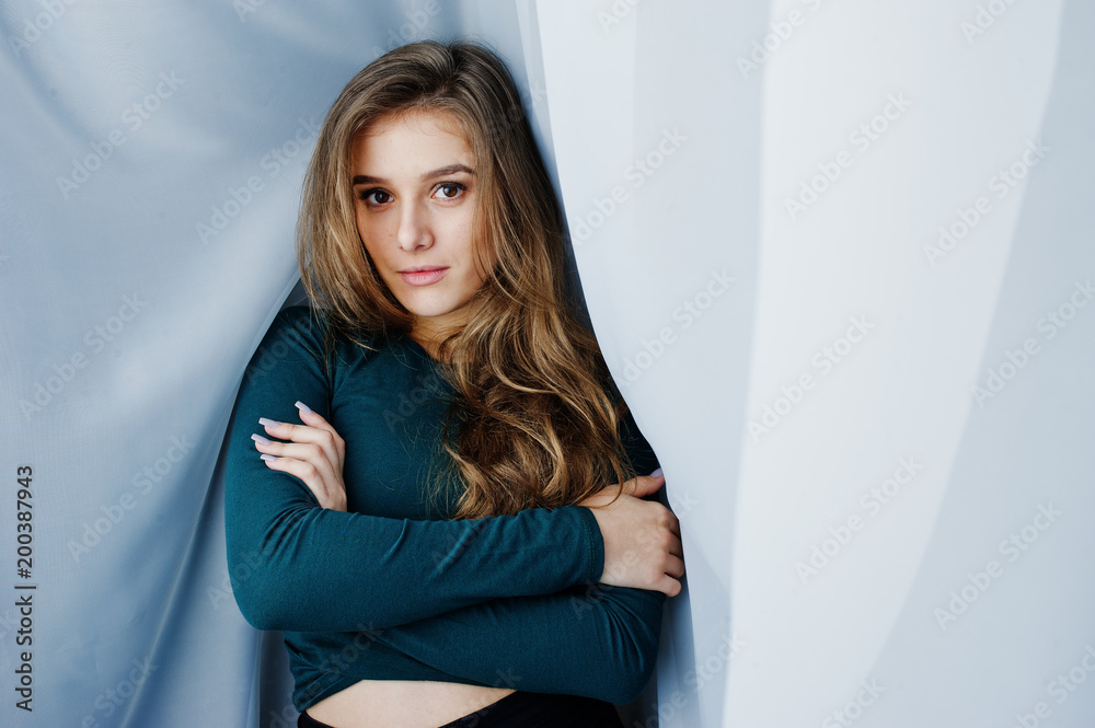 Handsome brunette girl wear on green, posing at curtains. Studio model portrait. Handsome brunette girl wear on green, posing at curtains. Studio model portrait.