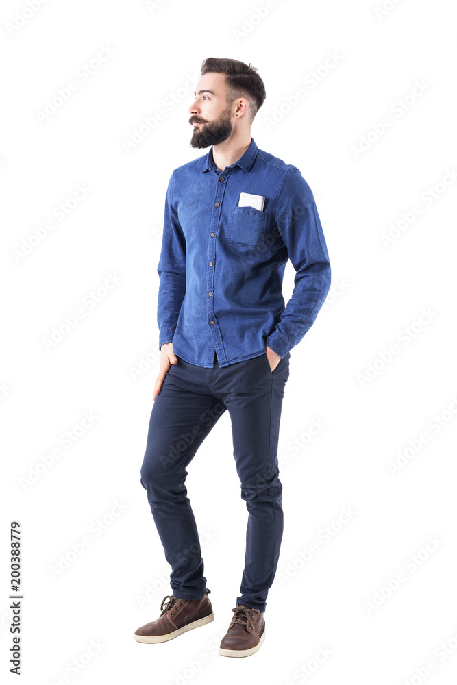 Cool relaxed young bearded business man with hands in pocket and mobile phone in shirt pocket looking away. Full body isolated on white background. Cool relaxed young bearded business man with hands in pocket and mobile phone in shirt pocket looking away. Full body isolated on white background.