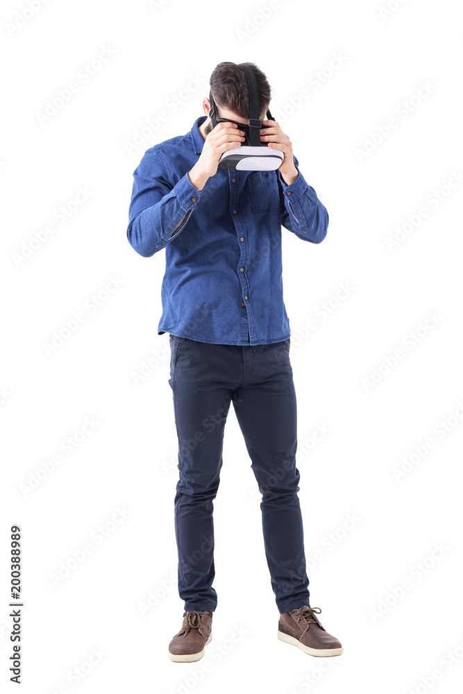 Young business man put on virtual reality headset adjusting and looking down. Full body isolated on white background. Young business man put on virtual reality headset adjusting and looking down. Full body isolated on white background.