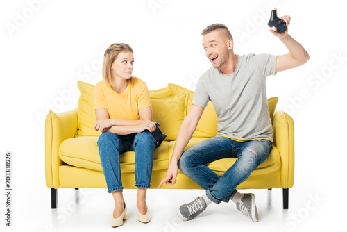couple on yellow sofa playing video game together isolated on white