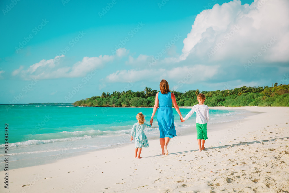 mother with son and daughter walk on beach