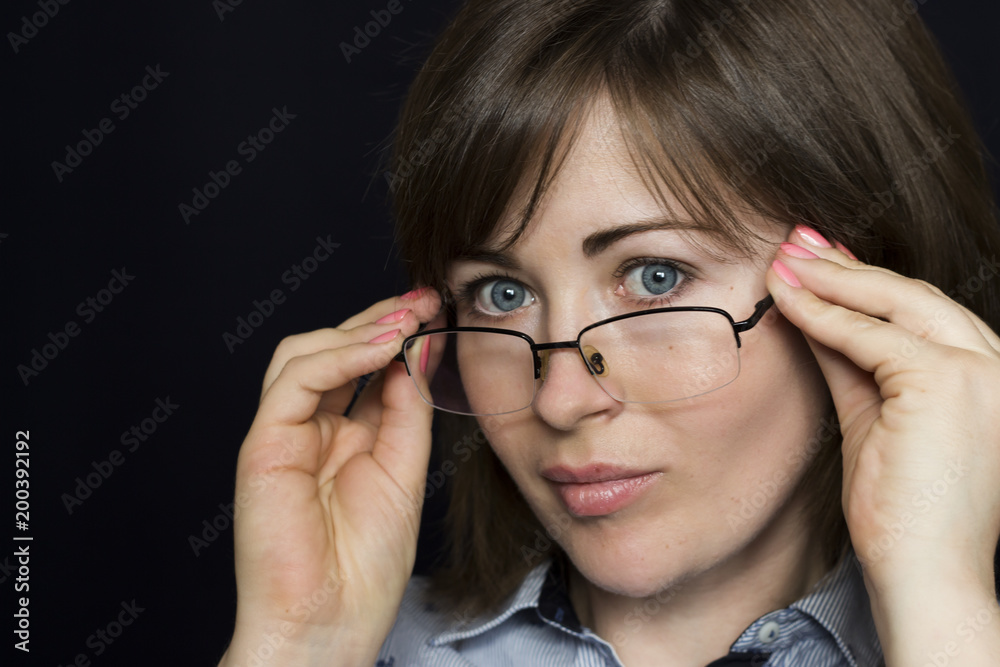 Portrait of a beautiful young, business woman wearing glasses. Close-up, isolated, black background Portrait of a beautiful young, business woman wearing glasses. Close-up, isolated, black background