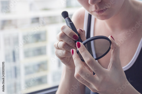 Fotografia girl photographer holding polarizing filter in her hands (cleaning the lens by special tool)