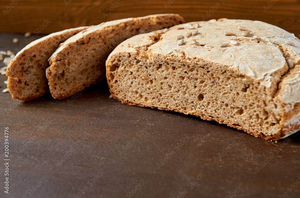 Homemade sliced appetizing fresh bread on the wooden background ready to eat. Just baked tasty bread on the brown table with free copy space. Side view