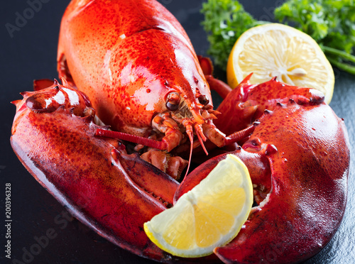 Red lobster with lemon and green on black wooden background photo