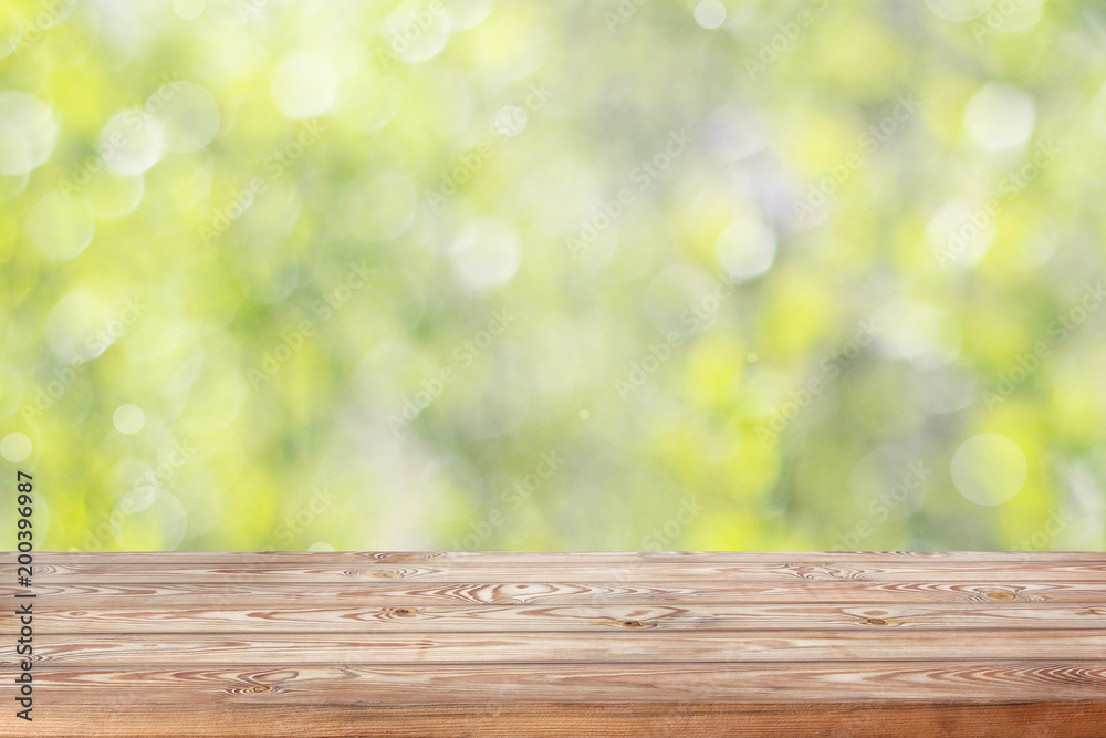 Empty wooden table top on blurred spring background with bokeh.