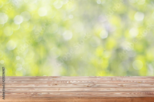 Empty wooden table top on blurred spring background with bokeh.