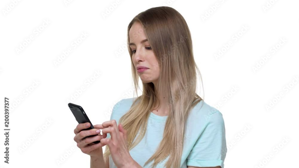 Portrait of caucasian woman 20s wearing basic t-shirt using smartphone and scrolling feed news in internet with different emotions, isolated over white background in studio Portrait of caucasian woman 20s wearing basic t-shirt using smartphone and scrolling feed news in internet with different emotions, isolated over white background in studio