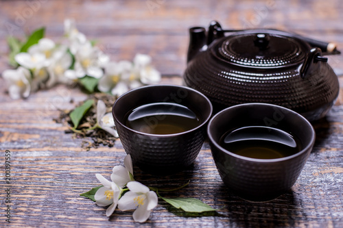 Tea cup, tea pot, jasmine flowers, green tea, mint, on wooden background