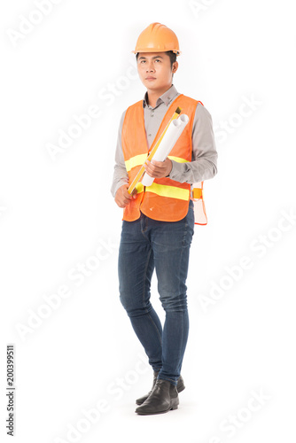 Studio portrait of construction worker in orange waistcoat and hardhat holding levelling tool and building plan