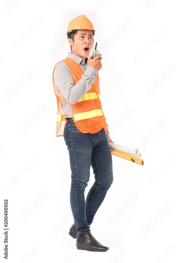 Studio portrait of construction worker in orange waistcoat and hardhat using walkie-talkie Studio portrait of construction worker in orange waistcoat and hardhat using walkie-talkie
