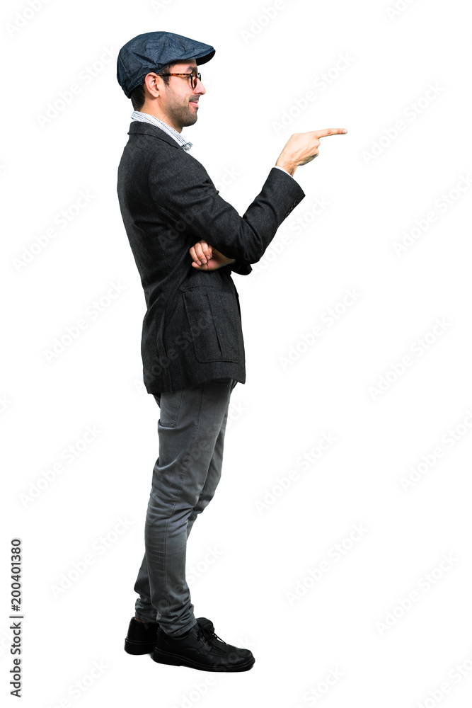 Handsome modern man with beret and glasses pointing finger to the side and presenting a product Handsome modern man with beret and glasses pointing finger to the side and presenting a product