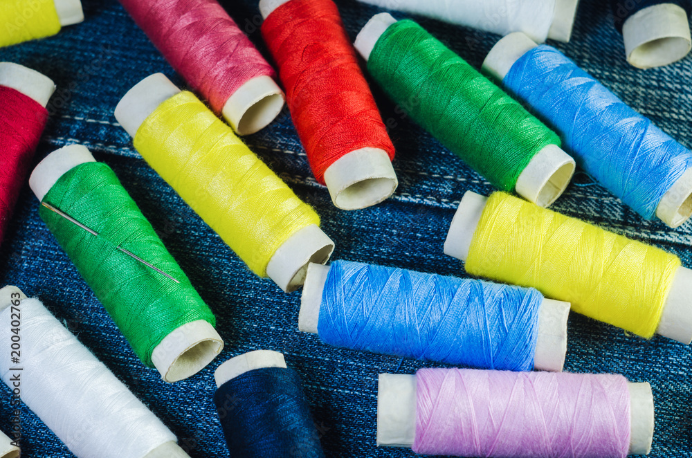 Spools of colored threads on denim fabric Spools of colored threads on denim fabric