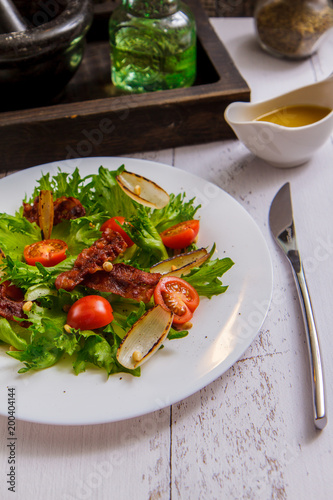 Crispy salad with bacon and cherry on a white plate side view