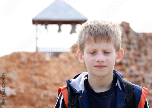 Boy with eyes closed against the old wall.
