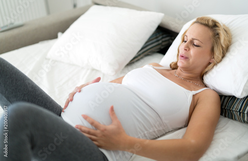 Tableau sur toile Pregnant blonde woman having contractions at home