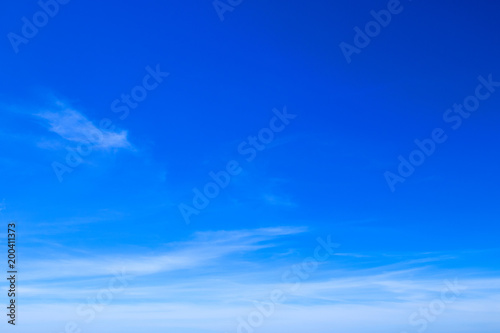 Brilliant blue sky background with sparse clouds in daylight.