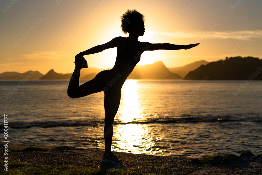 Silhouette of Fitness Woman Doing Stretching Exercise by Sunrise