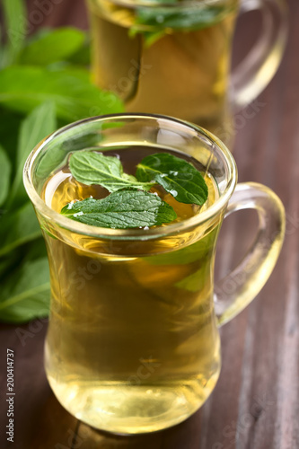 Freshly prepared mint herbal tea in glasses garnished with mint leaves (Selective Focus, Focus in the middle of the first leaf on the tea)