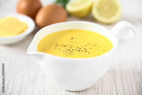 Hollandaise sauce, a basic sauce of the French cuisine, ingredients (egg, butter, lemon) in the back, photographed with natural light (Selective Focus in middle of the image)