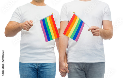 gay pride, lgbt and homosexual concept - close up of happy male couple with rainbow flags in white t-shirts holding hands