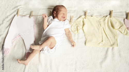 newborn infant and baby clothes on a wooden primako on a light b photo