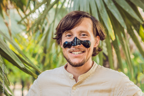 Happy man with black mask on the face. Photo of man receiving spa treatments. Beauty Skin care concept photo