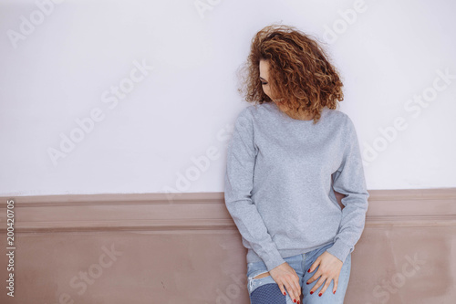 Curly haired girl with freckles in blank grey sweatshirt on the street. Mock up. photo