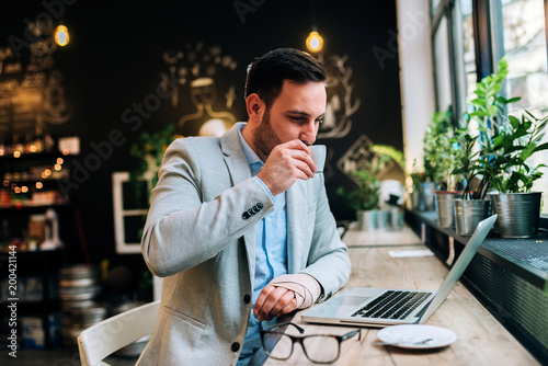 Businessman with bandaged hand drinking coffee in a cafe.