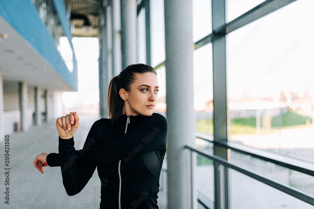 Fototapeta premium Attractive girl in black sportwear stretching arms. Close-up.