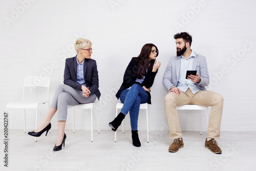 Three people talking to each other while waiting for job interwiev photo