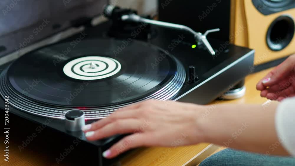 woman turns off the turntable takes the LP and finishes listening to music woman turns off the turntable takes the LP and finishes listening to music