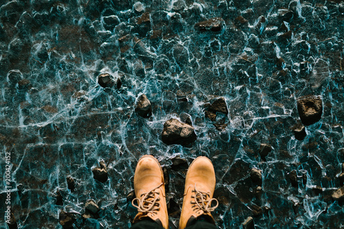 Man in a hiking boots stand on cracked ice background. Iceland. Top view