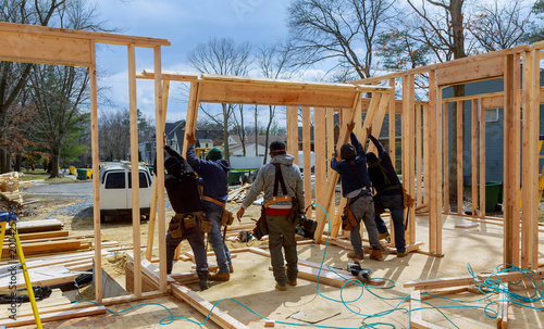 Construction Worker Using nail gun On wood building frame against
