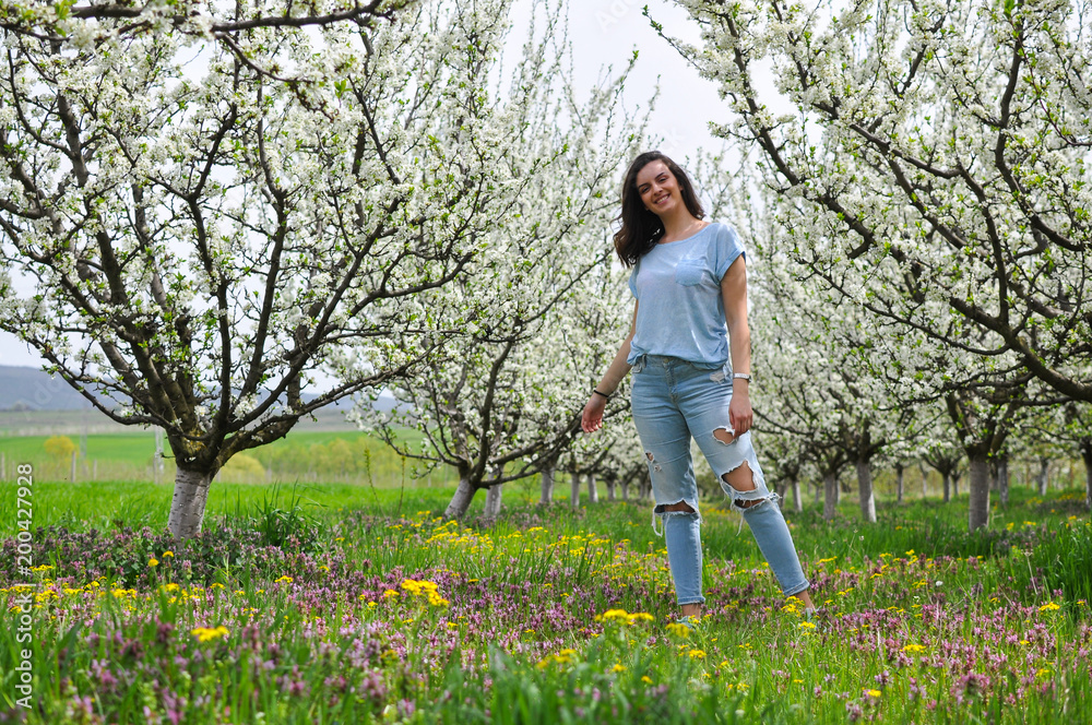 Portrait of happy girl in blooming orchard. Beautiful woman enjoy in nature in spring Portrait of happy girl in blooming orchard. Beautiful woman enjoy in nature in spring