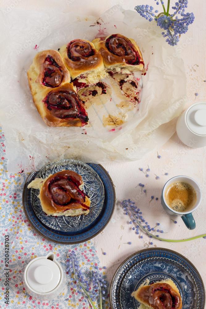 Blackberries buns. White background and blue plates. Coffee and flowers.