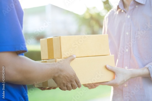 parcel delivery man of a package through a service. and close up hand customer accepting a delivery of boxes from delivery man postal.