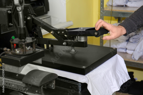 Foto Young man printing on t-shirt at workshop