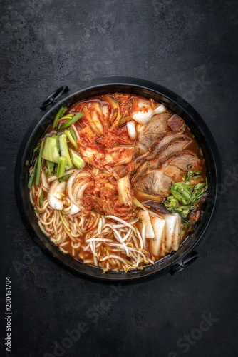 Traditional Korean kimchi jjigae with grilled pork belly and ramen as top view in a pot