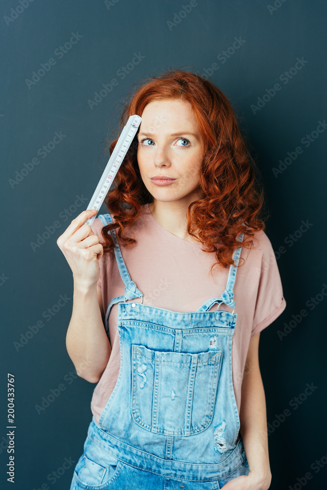 Fototapeta premium Thoughtful woman in dungarees pondering a problem