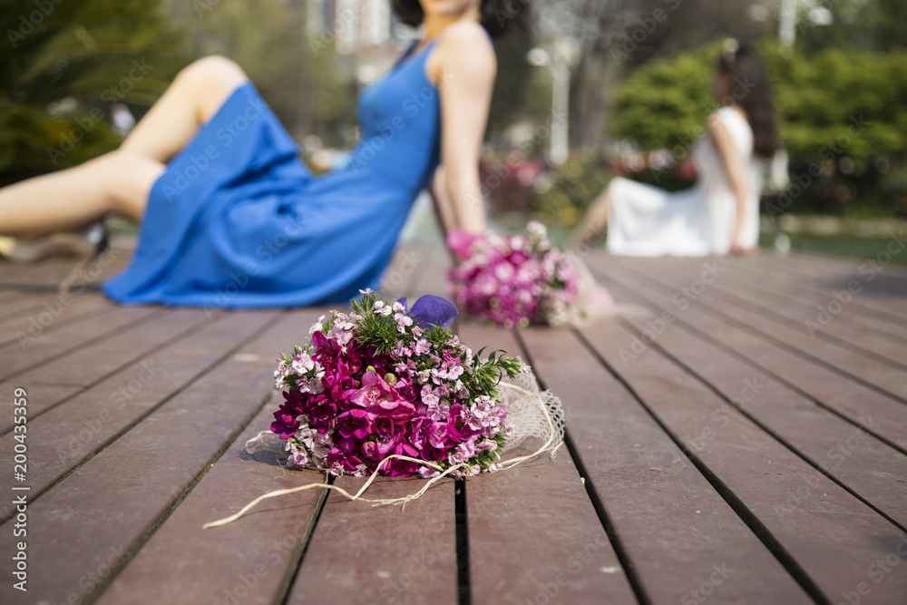 Bridal beautiful romantic bouquet of various flowers. Purple and pink flowers. girl in blue and white dress on the background. Bridal beautiful romantic bouquet of various flowers. Purple and pink flowers. girl in blue and white dress on the background.