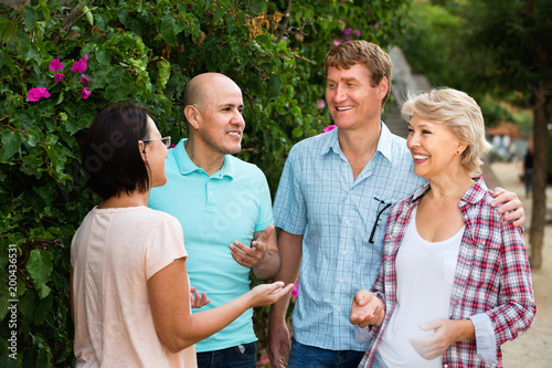  Portrait of mature cheerful males and females talking outdoors